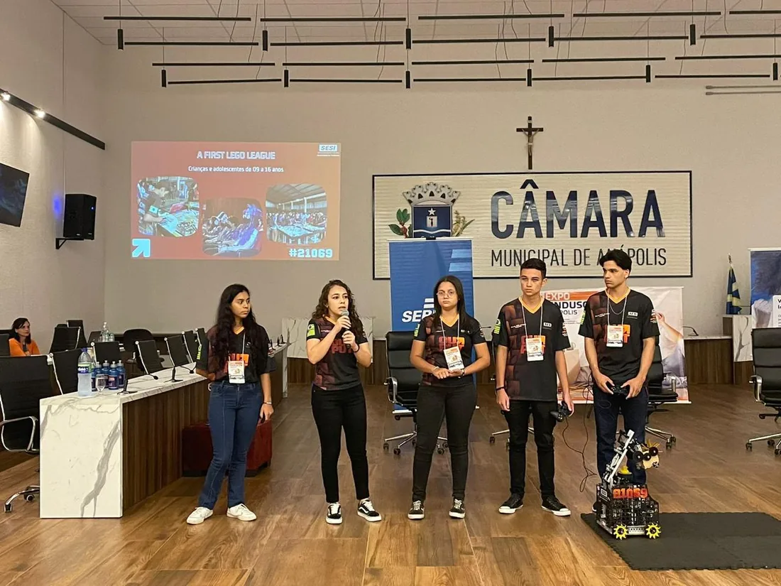 Apresentação técnica de projeto na Câmara Municipal de Anápolis, com o robô da equipe posicionado ao lado.